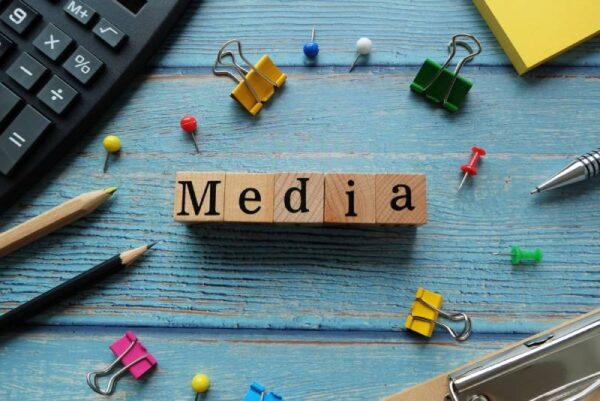 Wooden blocks spelling the word 'MEDIA' arranged on a blue background