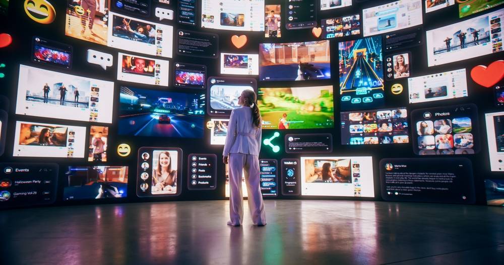 A woman stands before a simulated wall featuring many digital screens.
